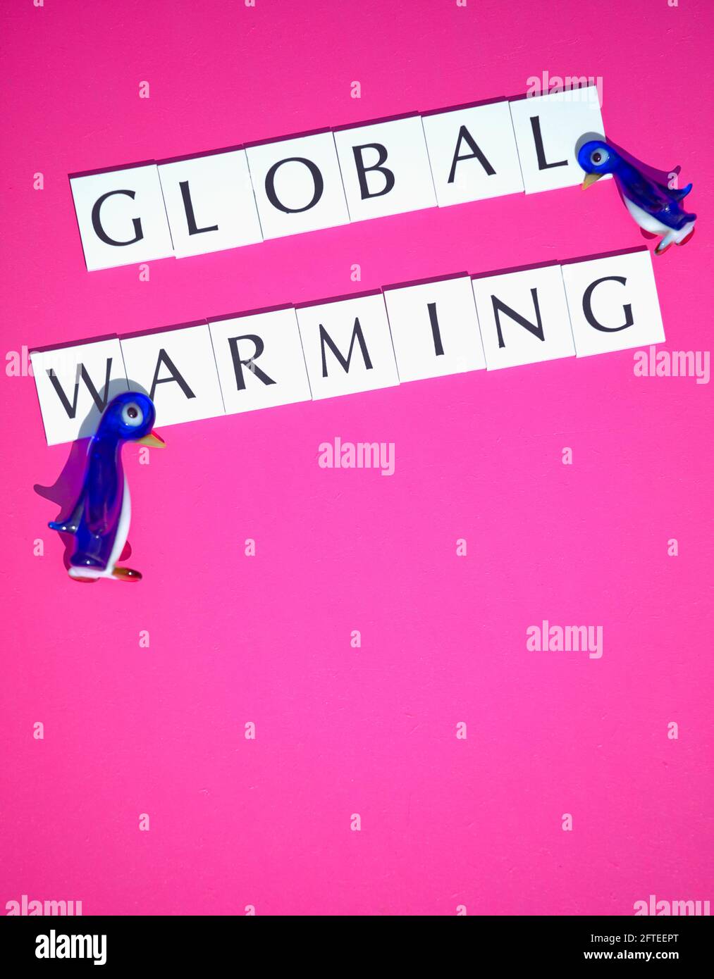 Direkt über zwei Glaspinguine und die Botschaft der globalen Erwärmung auf rosa Hintergrund. Konzept der Veränderung, Gefährdung des Lebensraums, Schutz der Tierwelt Stockfoto