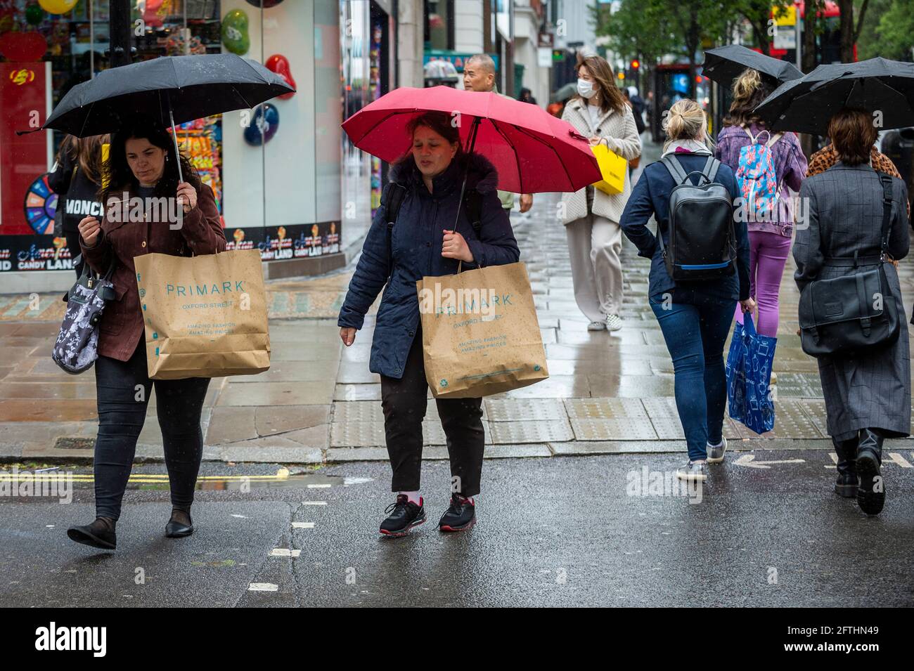 London, Großbritannien. Mai 2021. Menschen, die im Regen in der Oxford Street einkaufen. Das Office for National Statistics (ONS) hat berichtet, dass die Einzelhandelsumsätze im April um 10 % über dem Stand vor der Pandemie lagen, wobei der Absatz von Kleidung im Vergleich zum März um 70 % gestiegen ist. Es wurde vermutet, dass der Anstieg ein Beleg für die aufgestaute Nachfrage ist, da am 12. April in England wieder Geschäfte eröffnet wurden, die nicht unbedingt notwendig sind. Kredit: Stephen Chung/Alamy Live Nachrichten Stockfoto