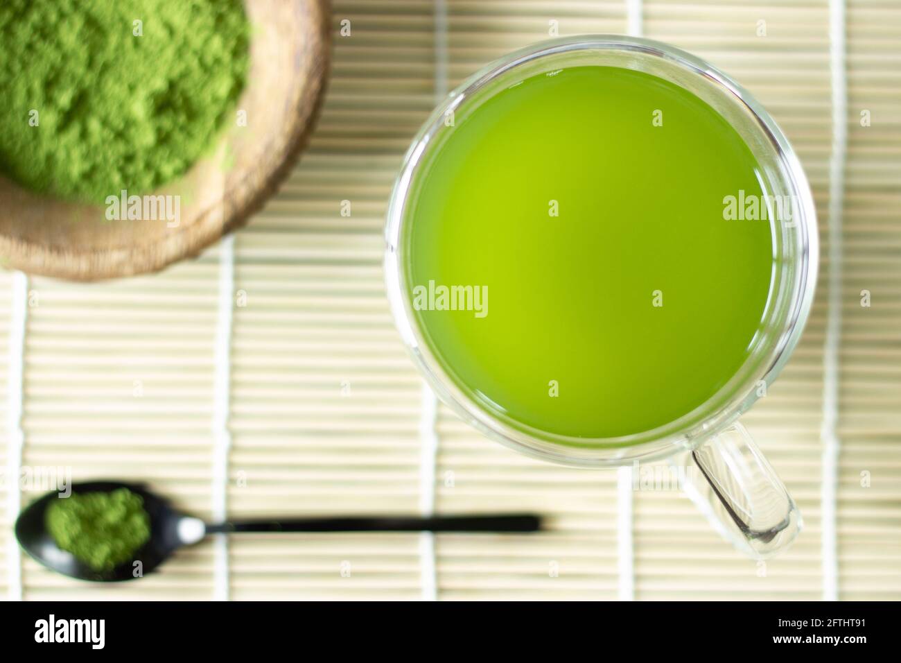 Matcha-Getränk und -Pulver auf Bambusmatte; japanischer grüner Tee; Servieren; Matcha auf Löffel; Tasse grüner Matcha-Tee Stockfoto