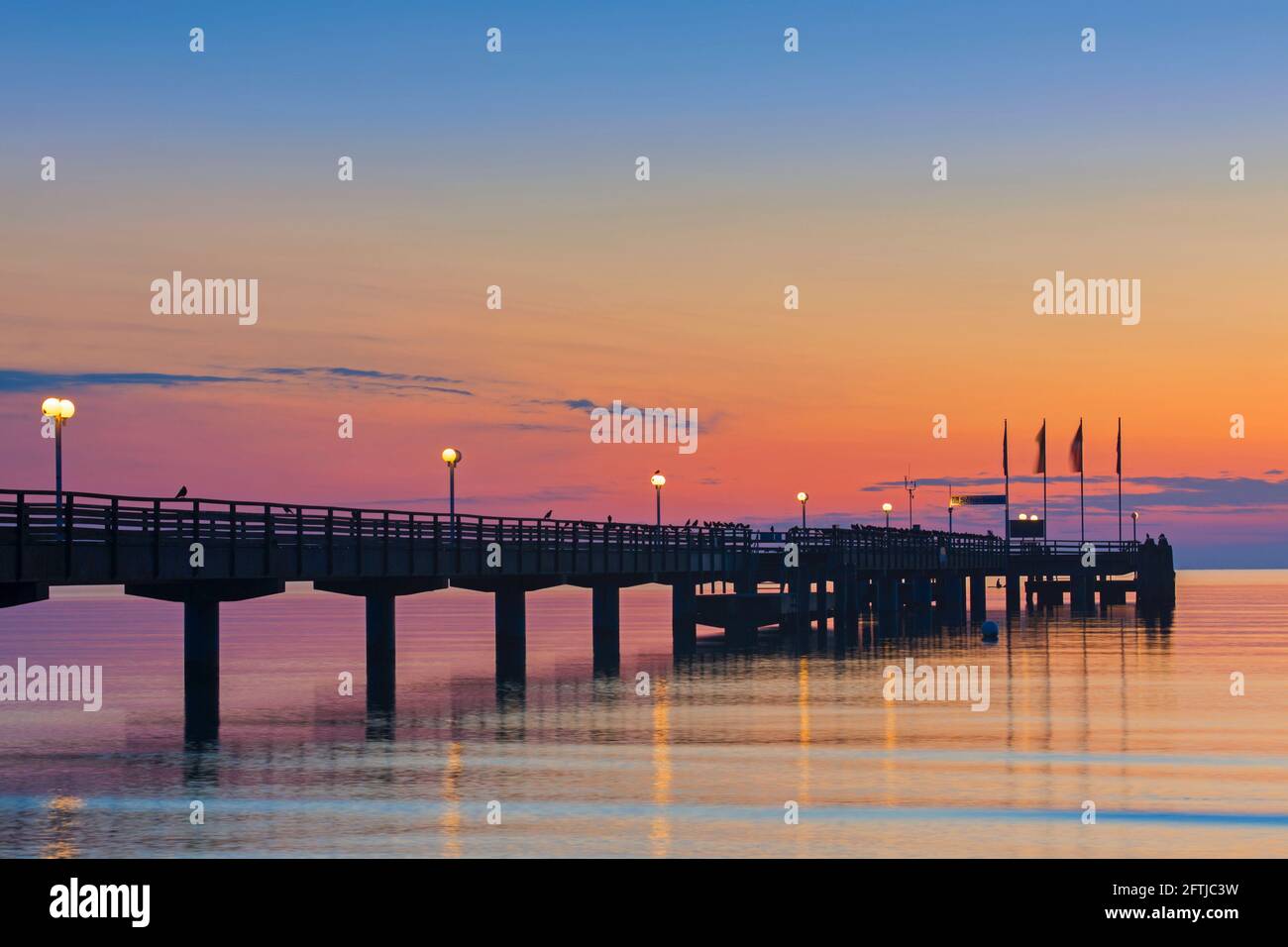 Beleuchtete Holzsteg / Seebrücke am Badeort Scharbeutz bei Sonnenaufgang, Ostholstein entlang der Lübecker Bucht, Schleswig-Holstein, Deutschland Stockfoto