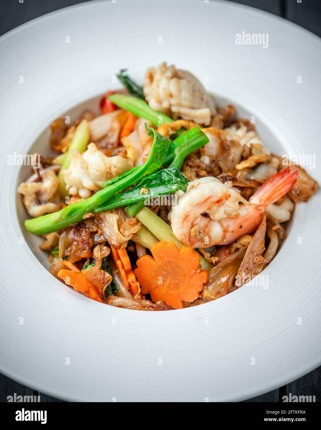 Ein Gericht Thai Pad See EW Noodle with Seafood Und Gemüse auf schwarzem Holzhintergrund Stockfoto