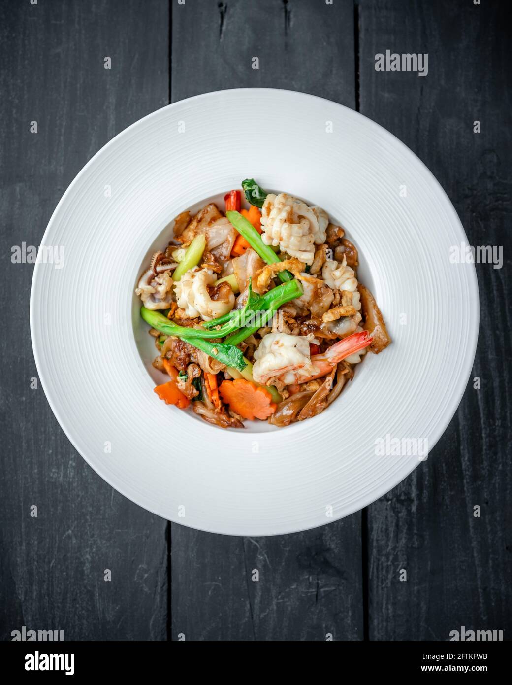 Ein Gericht Thai Pad See EW Noodle with Seafood Und Gemüse auf schwarzem Holzhintergrund Stockfoto