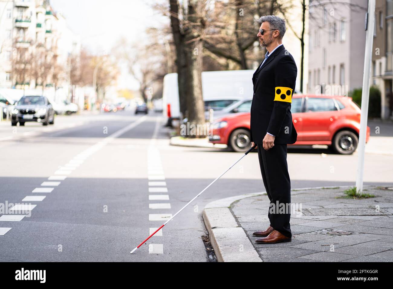 Blinden Mann zu Fuß auf dem Bürgersteig Holding Stick mit Armband Stockfoto