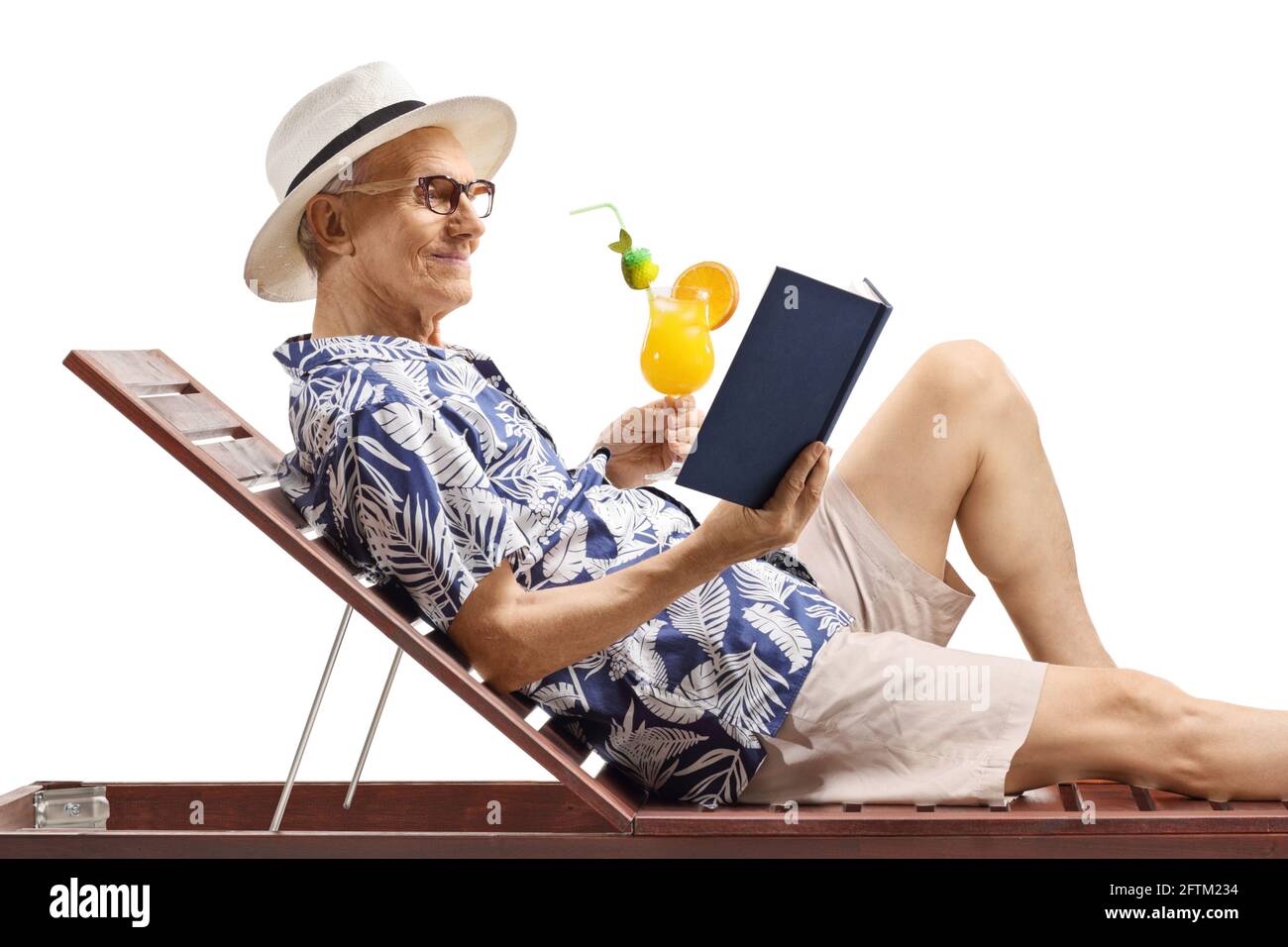 Ein älterer Mann auf einem Liegebett, der ein Buch und las Hält einen Cocktail isoliert auf weißem Hintergrund Stockfoto