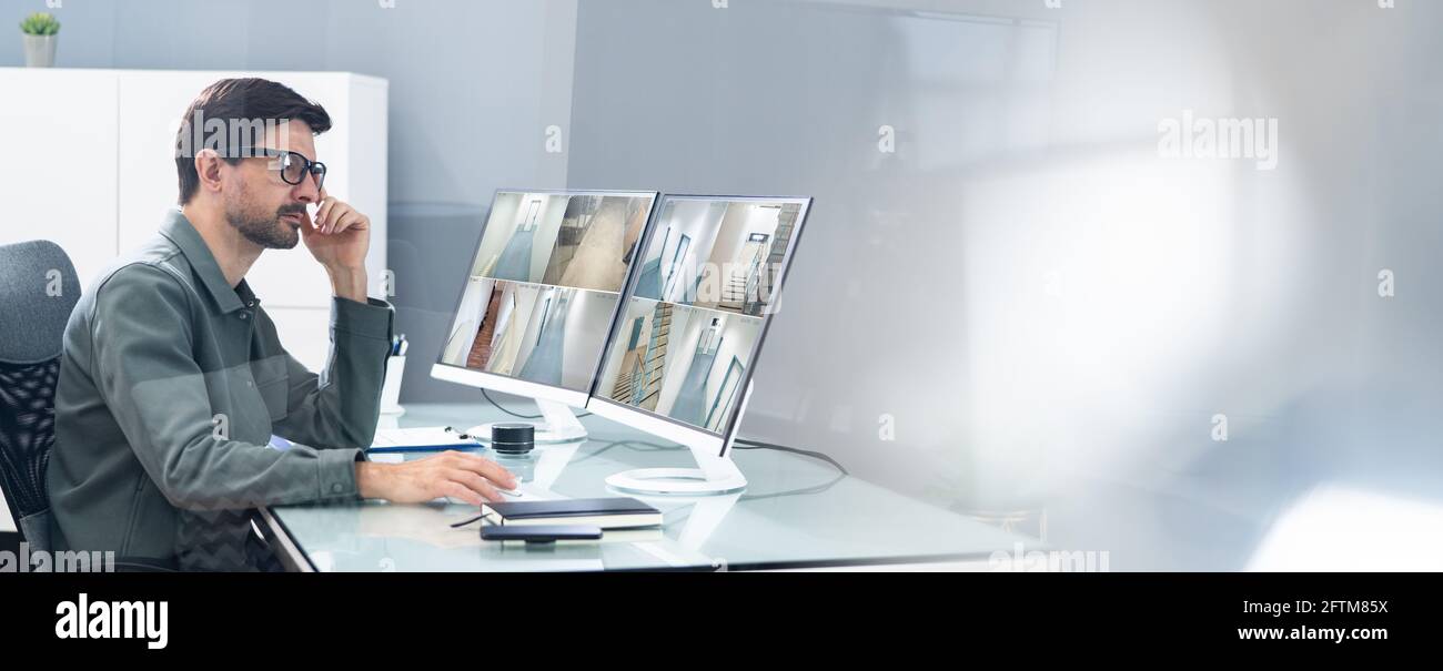 Der Bediener des Sicherheitssystems sieht sich CCTV-Aufnahmen am Schreibtisch an Büro Stockfoto