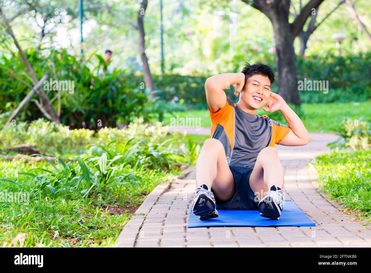 Asiatischer mann Crunches für Six Pack Training in Park Stockfoto