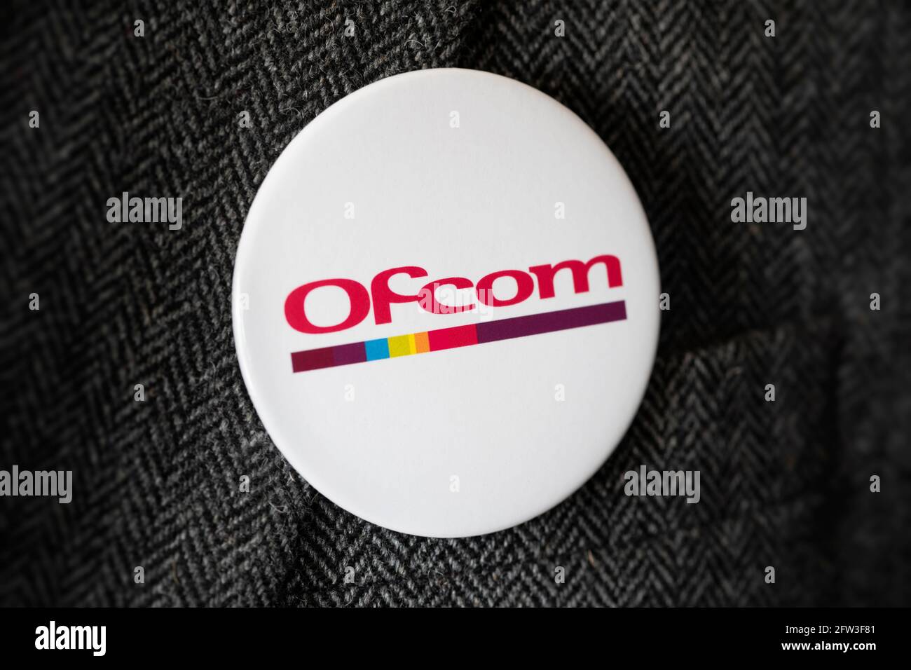 Ein Knopfabzeichen mit dem Logo des Ofcom Kommunikationsreglers, das an einer Jacke befestigt ist. Stockfoto