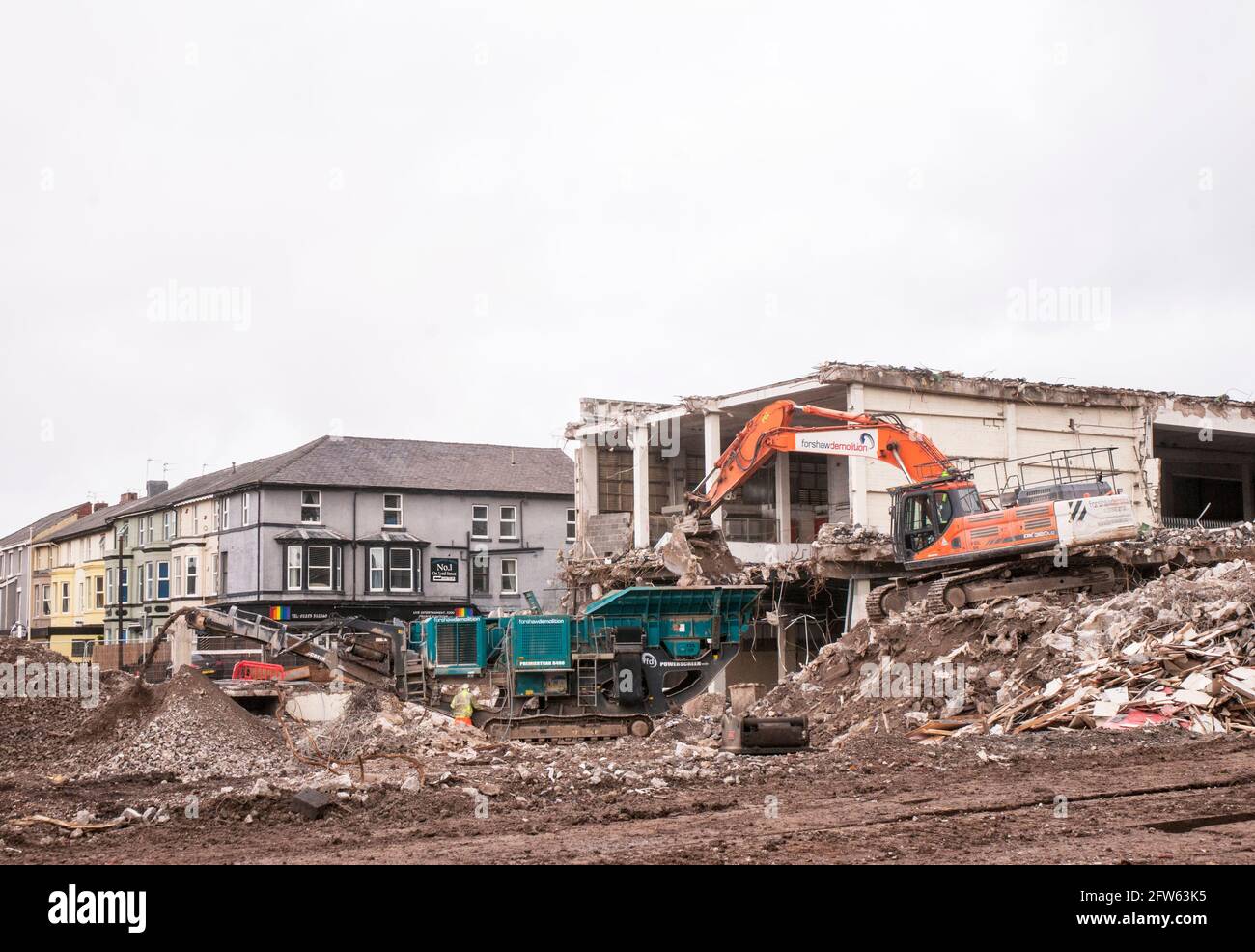 Mechanischer Bagger, der Stein und Schutt auf einer Steinbrechmaschine auf der Abbruchstelle in einen Trichter verladen hat. Der Schotter wird vor Ort gelagert Stockfoto