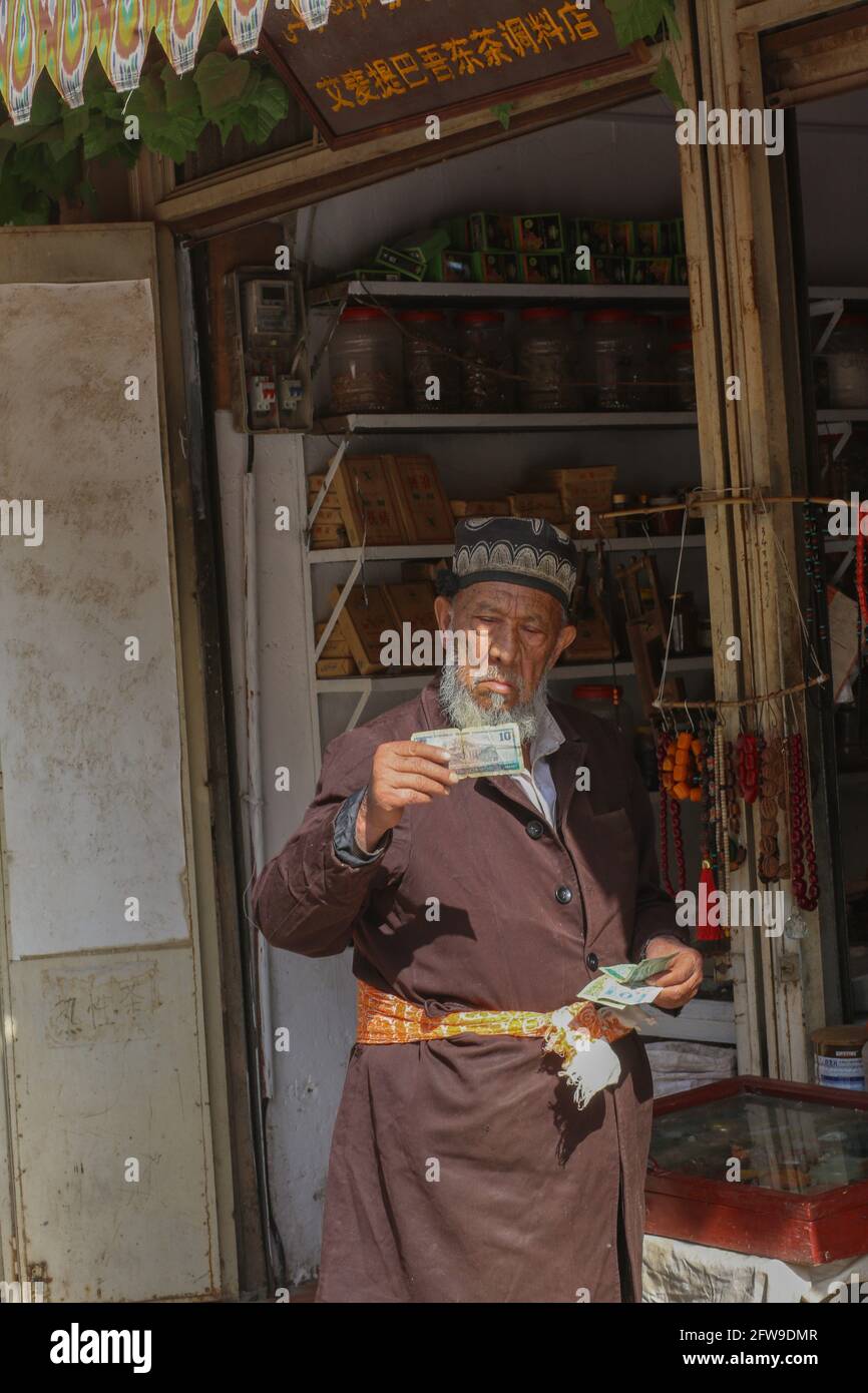 Alter Mann, der im Hintergrund ausländisches Geld sieht Kashgar, Xinkiang, Volksrepublik China, 2019 Stockfoto