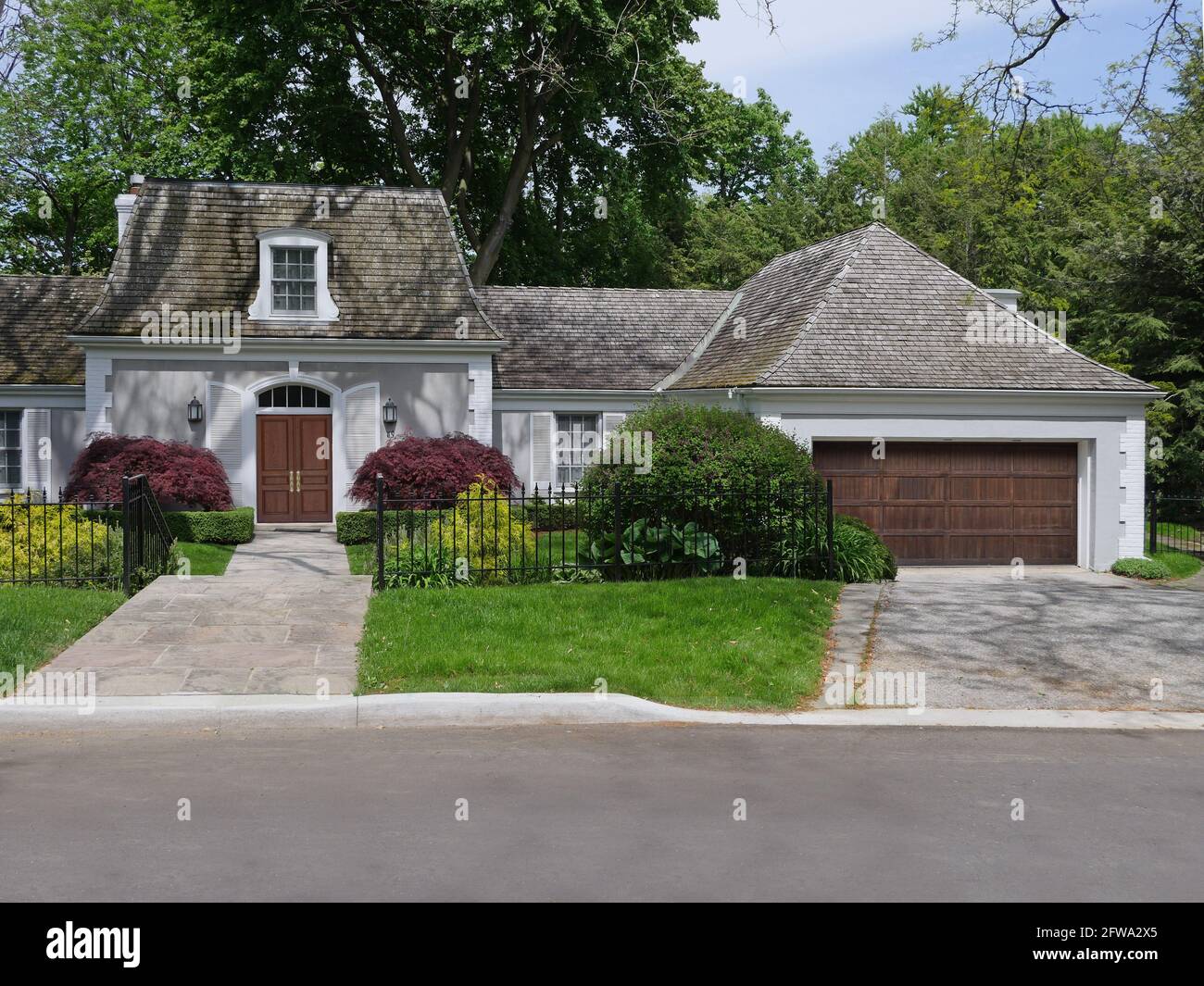 Vorstadthaus mit Zedernschindeldach und Dachfenster, Holzvorbau-Vordertür und Doppelgaragentür Stockfoto