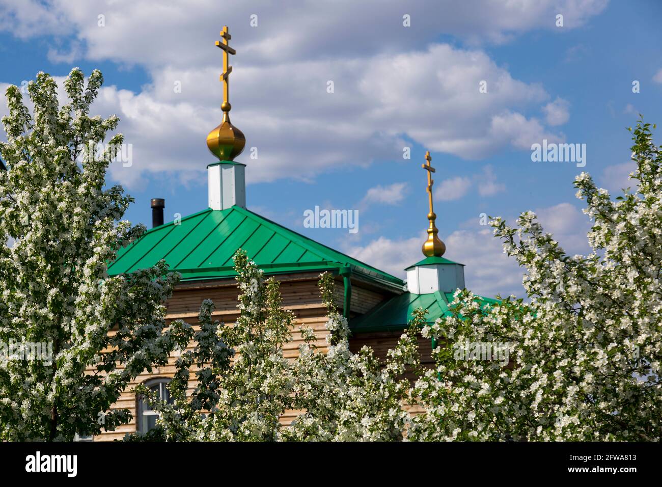 Der Apfelgarten blüht neben der orthodoxen Kirche gegen Der blaue Himmel Stockfoto