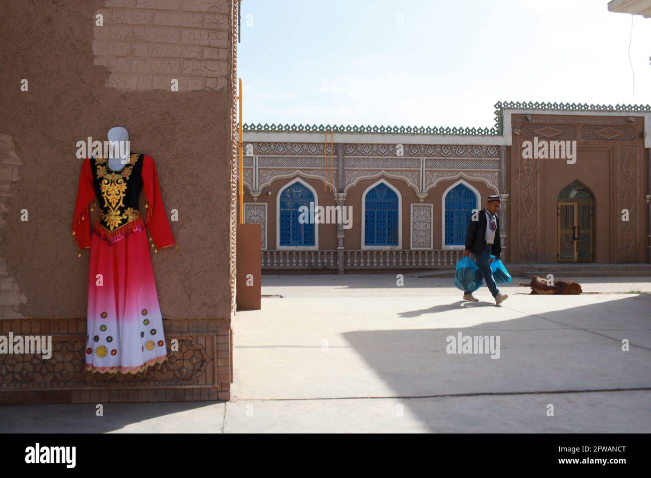 Ein traditionelles und festliches Kleid, das an einer Wand hängt. Kashgar, Xinkiang, Volksrepublik China, 2019 Stockfoto