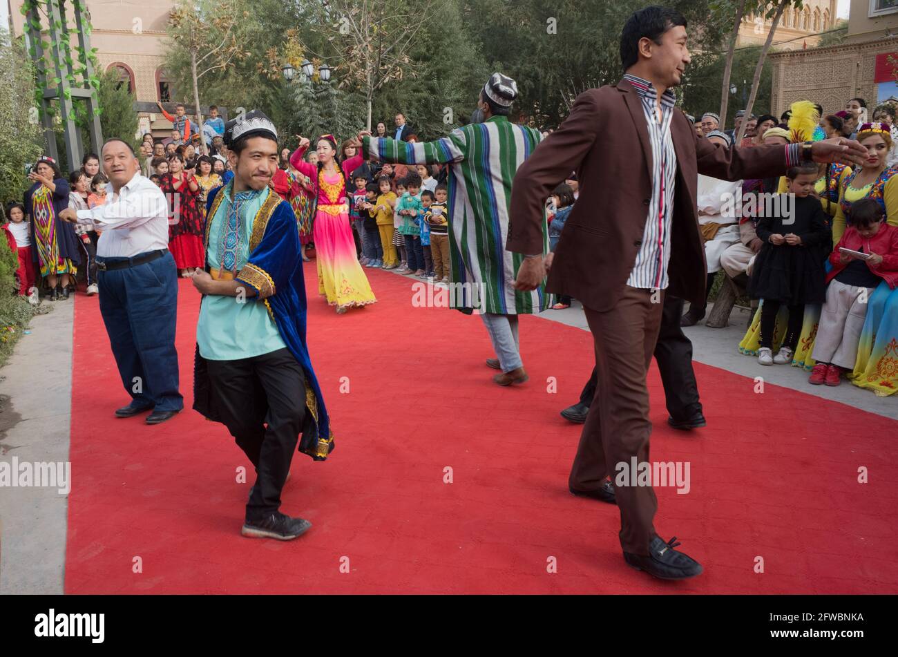 Männer und Frauen der uigurischen Volksgruppe tanzen auf einem quadratischen Kashgar, Xinkiang, Volksrepublik China, 2019 Stockfoto