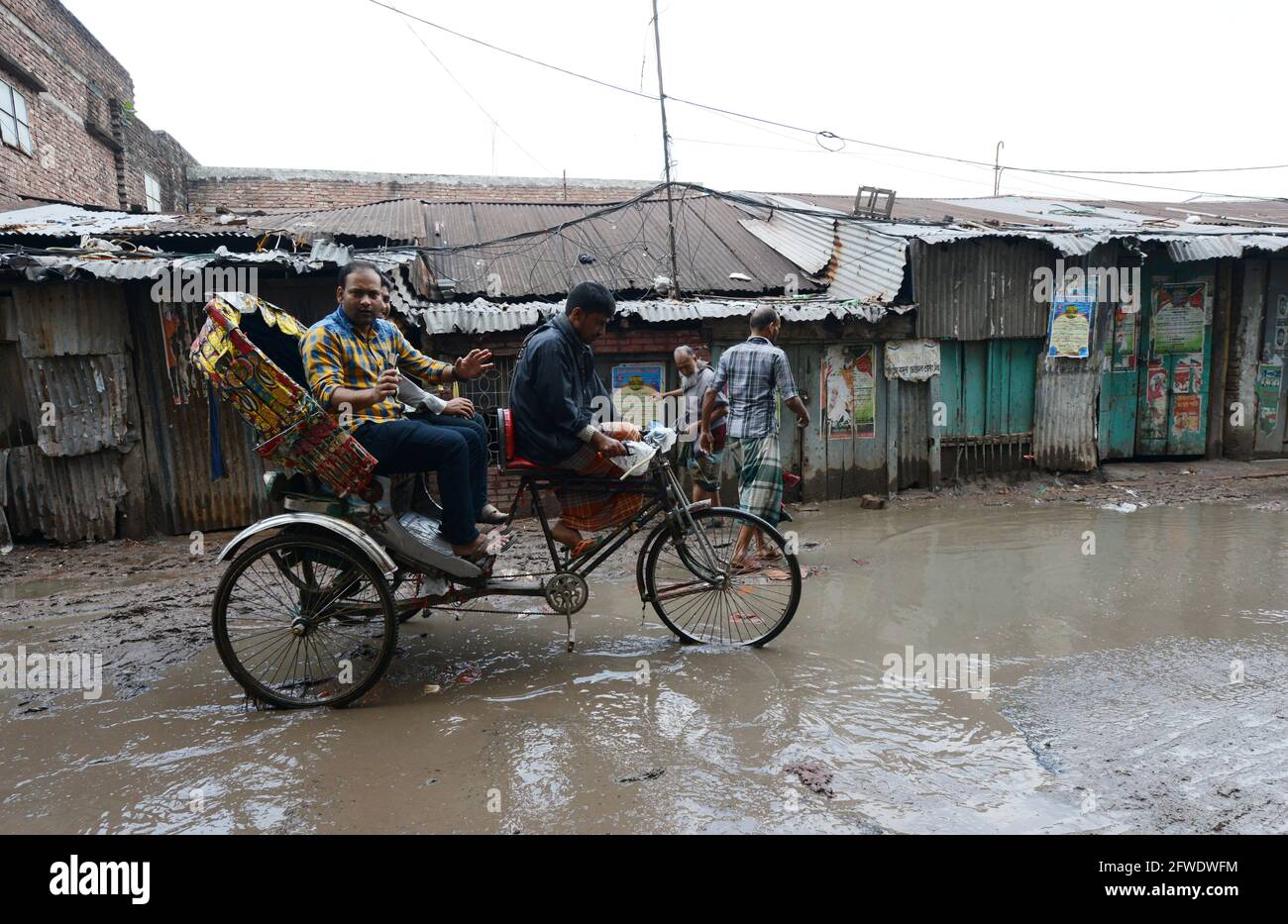 Radfahren auf einer schlammigen Straße während der Regenzeit im alten Dhaka, Bangladesch. Stockfoto