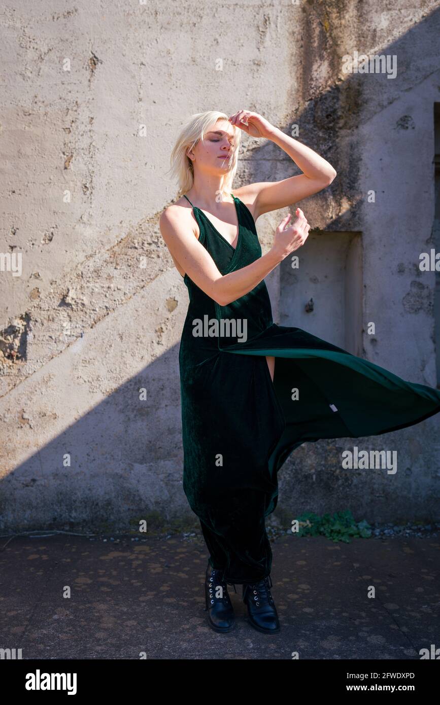 Mode an ungewöhnlichen Orten, Frau in langen Kleidern steht in Ruinen von Waffenbatterien | Kleid bläst im Wind Stockfoto