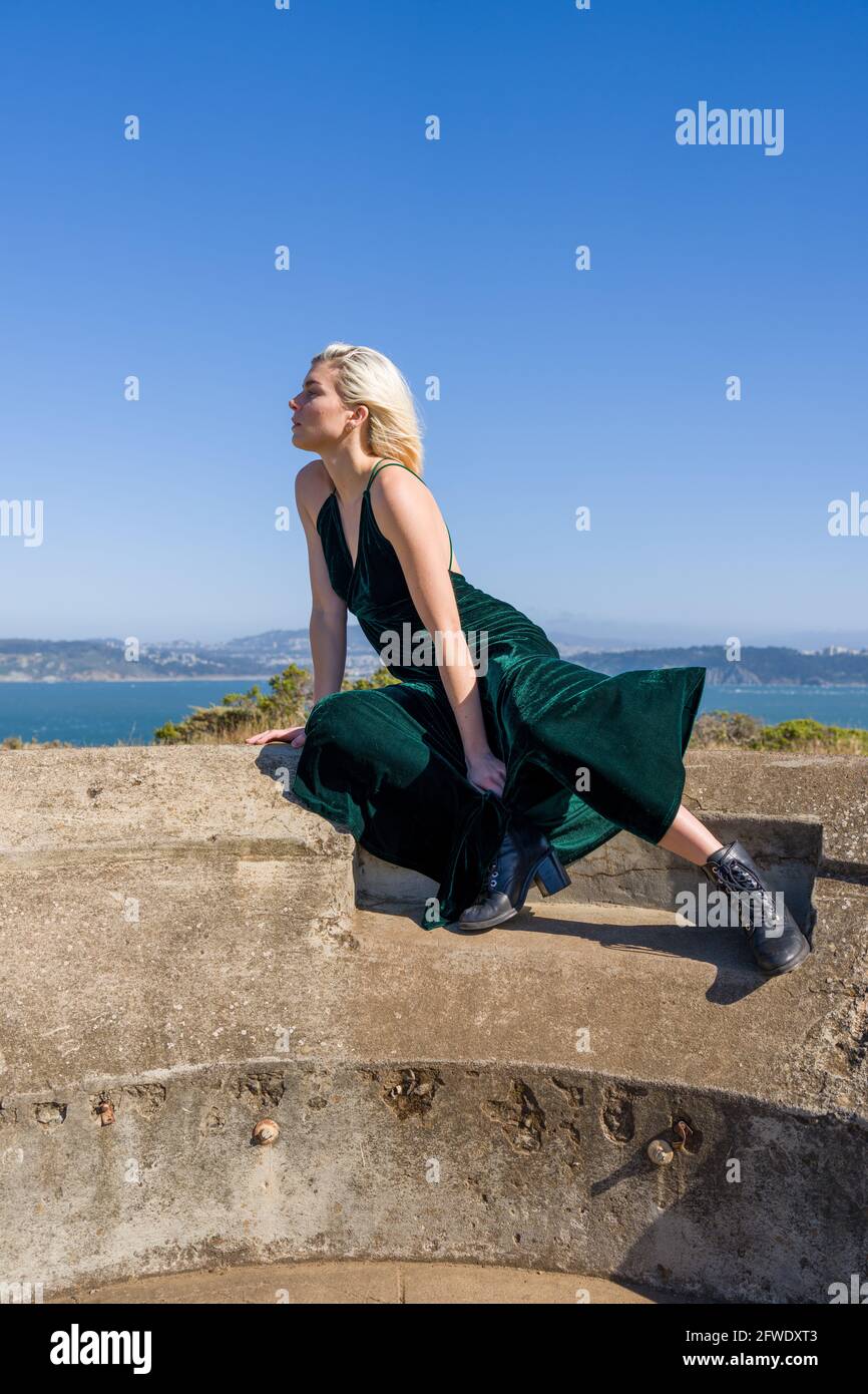 Mode an ungewöhnlichen Orten, Frau in voller Länge Kleid steht in Ruinen der Waffe Batterie Stockfoto
