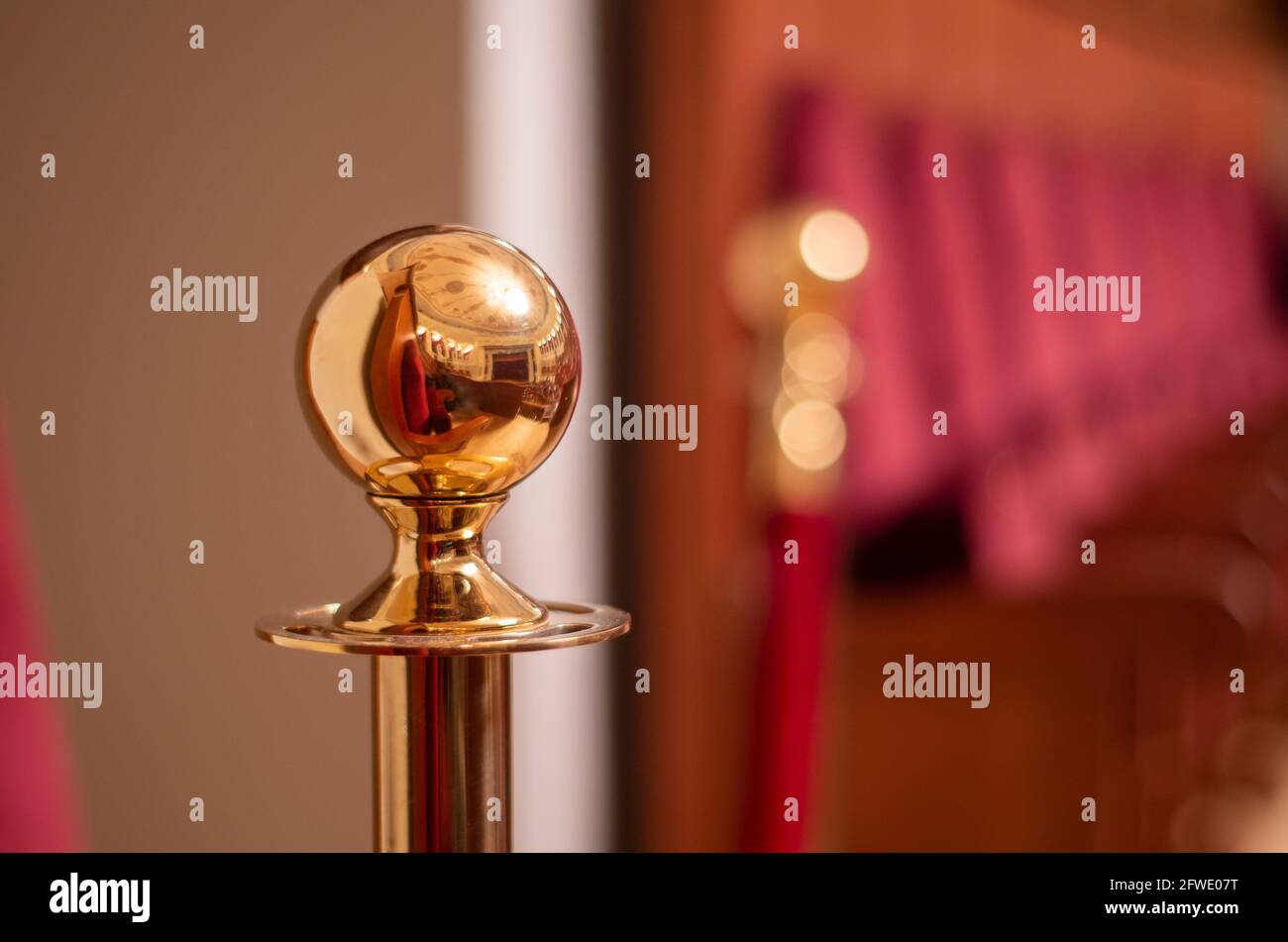 Fragment eines goldenen Leuchters auf einem unscharfen Hintergrund roter Theaterstühle. Stockfoto