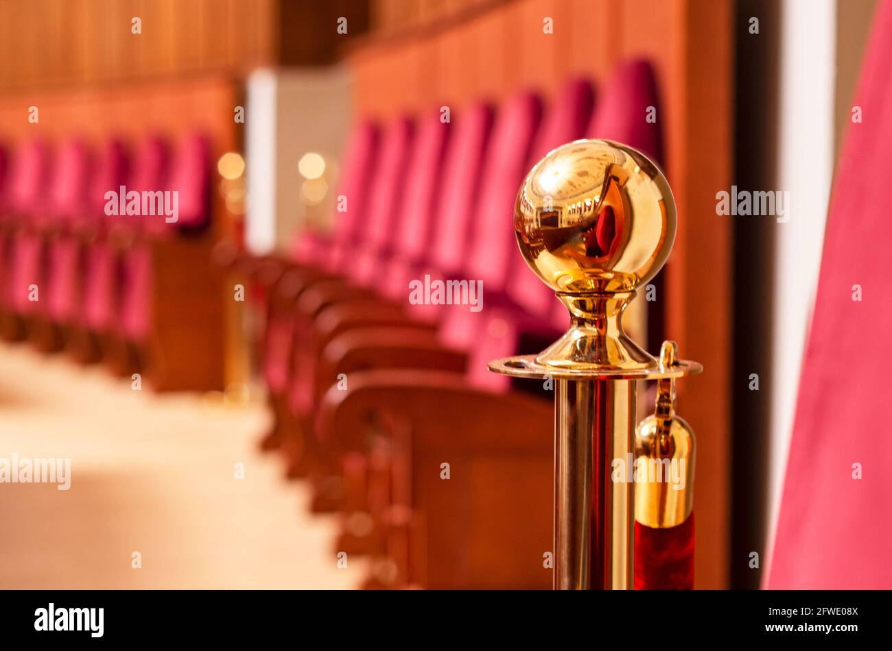 Fragment eines goldenen Leuchters auf einem unscharfen Hintergrund roter Theaterstühle. Stockfoto