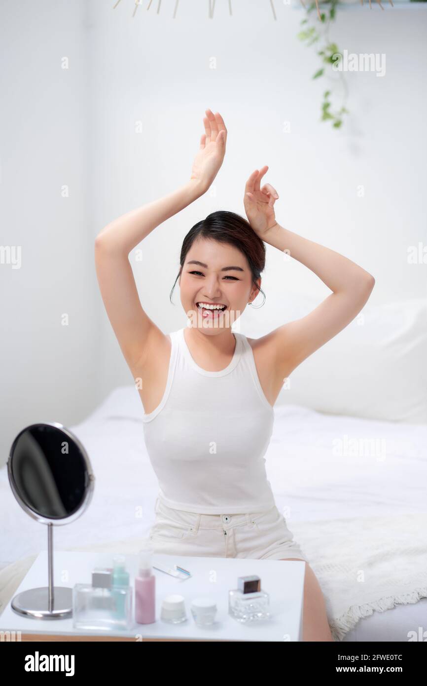 Schlanke junge Frau zeigt zarte, glatte Achselhaut im Schlafzimmer Stockfoto