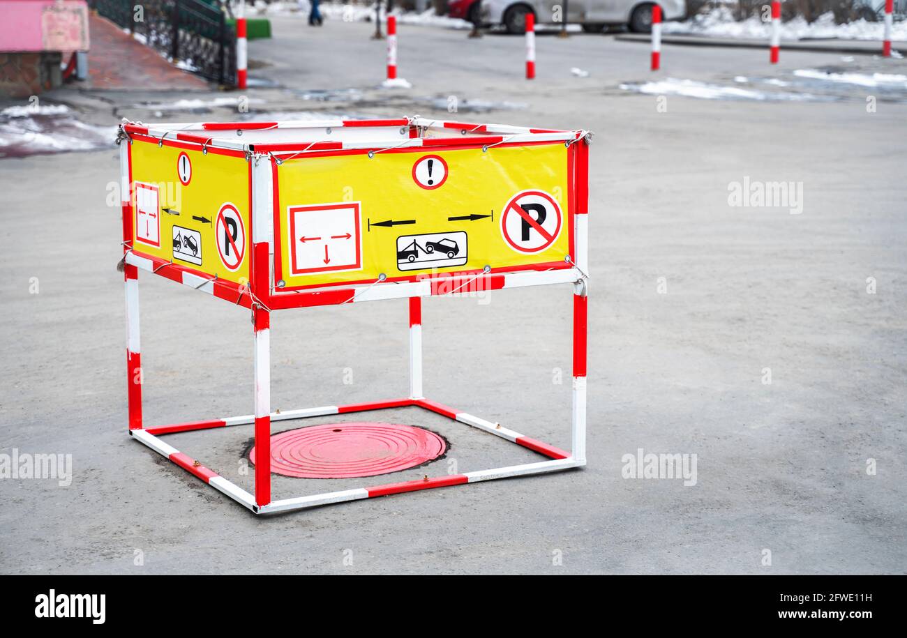 Straßenarbeiten auf den Straßen im Stadtzentrum. Rotes Schachtloch, die Luke ist für die Sicherheit von Passanten und Autos eingezäunt Stockfoto