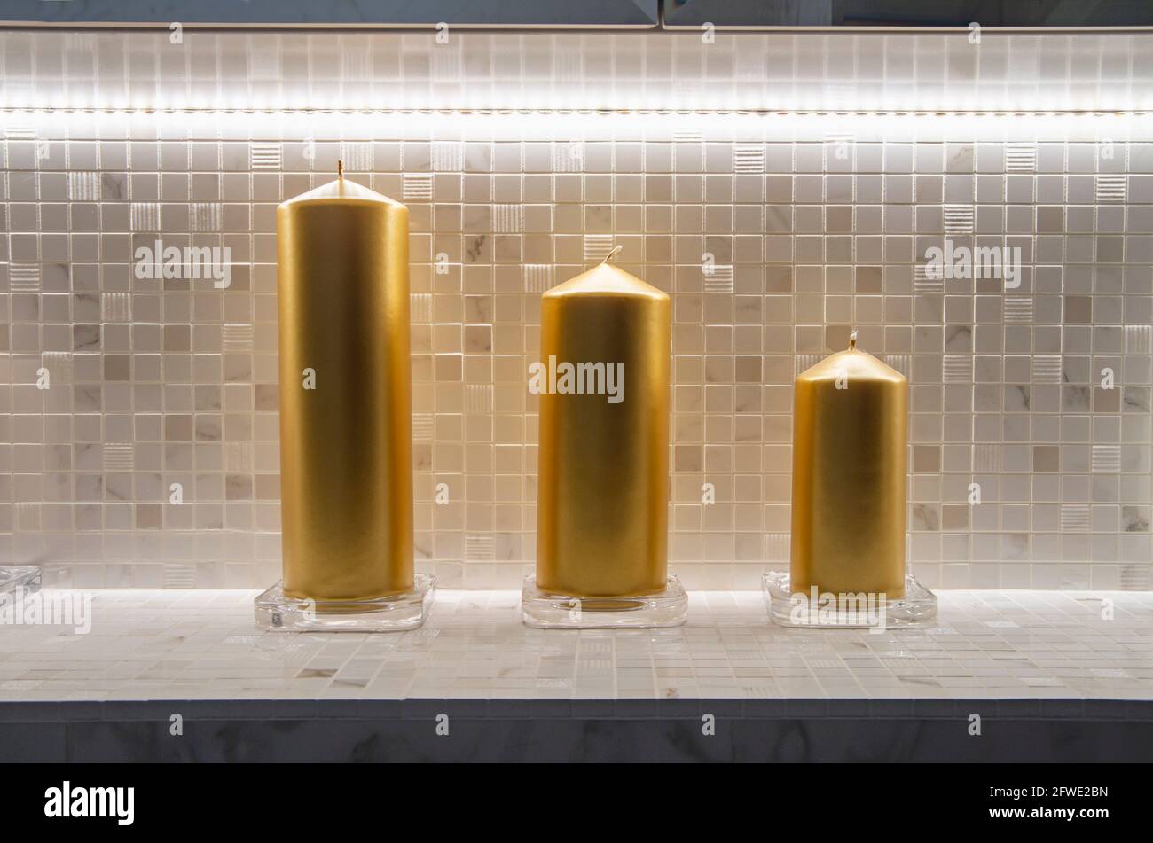 Graues und helles Regal mit dekorativen Golden Candles im Badezimmer vor dem Hintergrund von Spiegeln Stockfoto