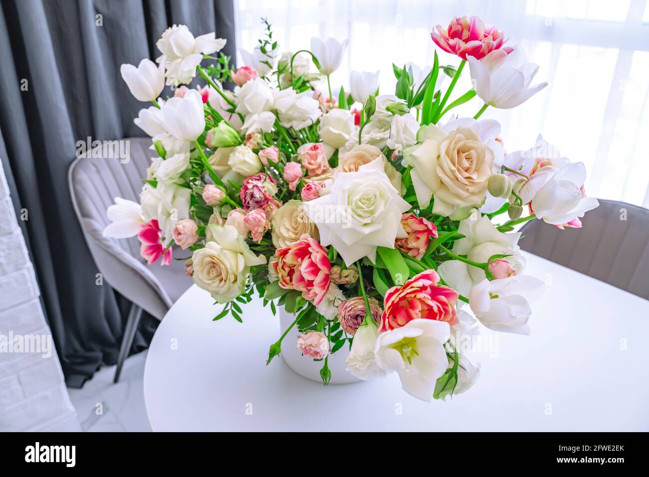 Bouquet von rosa und weißen Tulpen und Rosen schmückt den Konferenztisch, heller Hintergrund, Platz für Text. Spring сard, Banner. Stockfoto