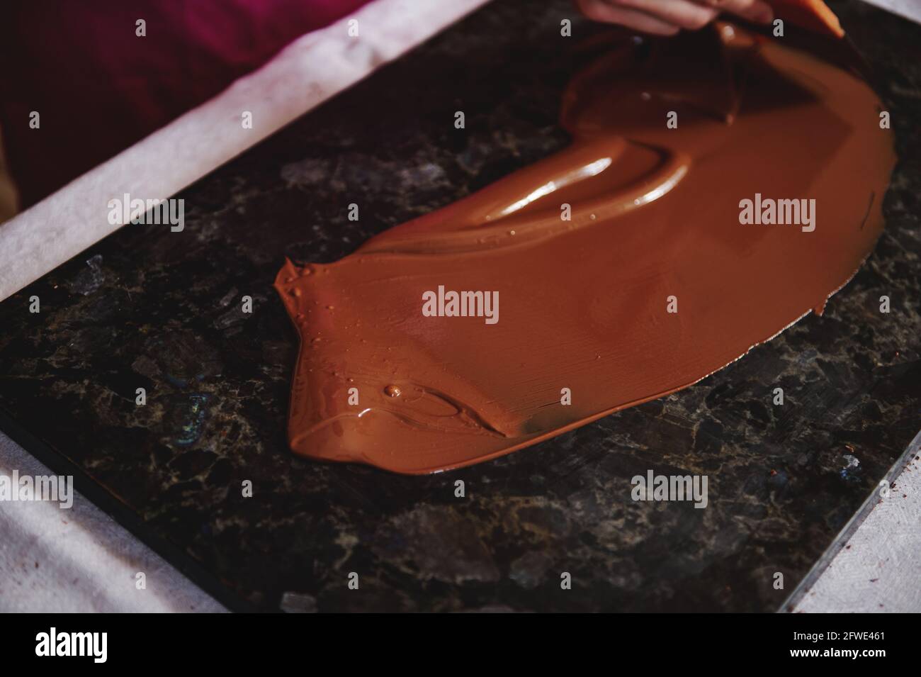 Blick in den hohen Winkel auf das Anlassen der Schokoladenmasse im Dunkeln Marmoroberfläche Stockfoto