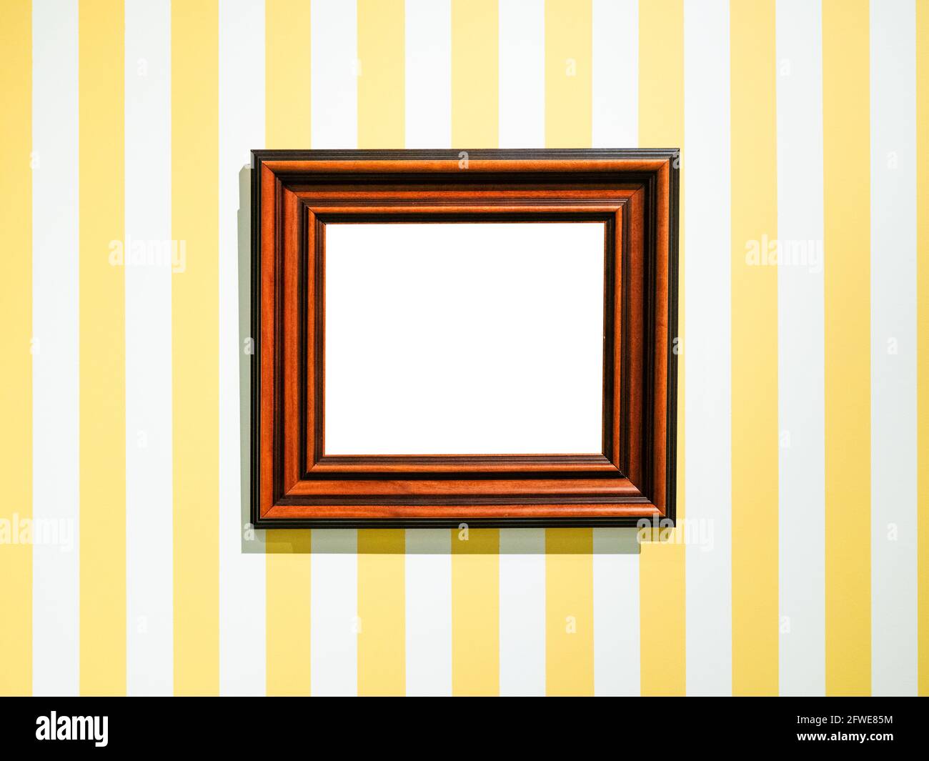 Breiter rotbrauner Holzbildrahmen mit Ausschnitt auf Leinwand Gestreifte gelbe Wand Stockfoto