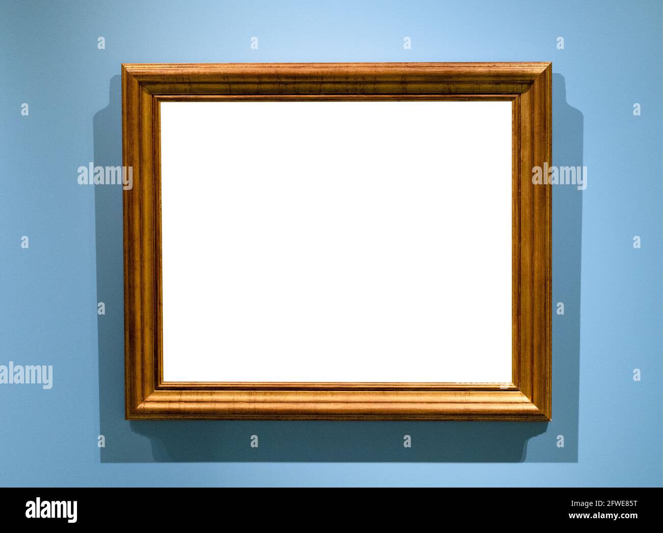 Natürlicher brauner Holzbilderrahmen mit ausgeschnitter Leinwand auf horizontaler Ebene Blaue Wand Stockfoto