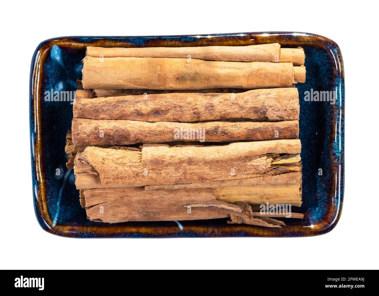 Draufsicht auf Stäbchen mit kontinentalem ceylon-Zimt in Keramik Schüssel Ausschnitt auf weißem Hintergrund Stockfoto