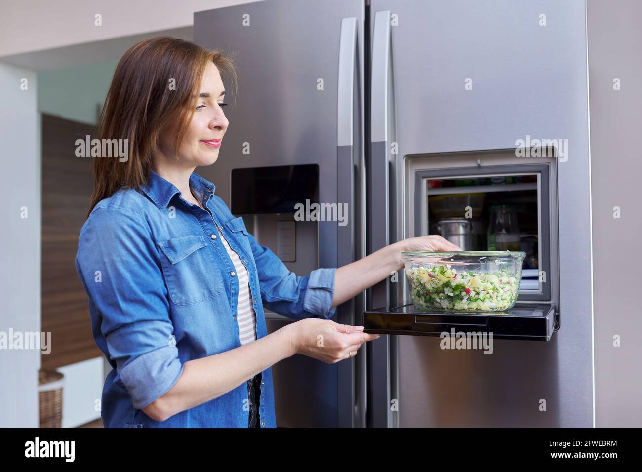 Frau mit Schale Gemüsesalat aus dem Kühlschrank. Stockfoto