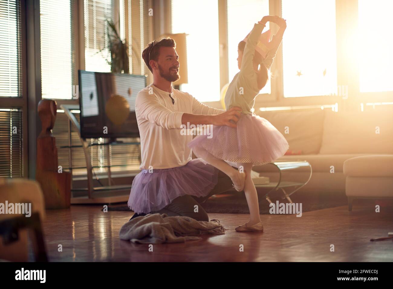Ein kleines Mädchen hat eine Unterstützung durch ihren Vater mit ihren Ballettzügen in einer schönen Atmosphäre zu Hause. Familie, zusammen, zu Hause Stockfoto