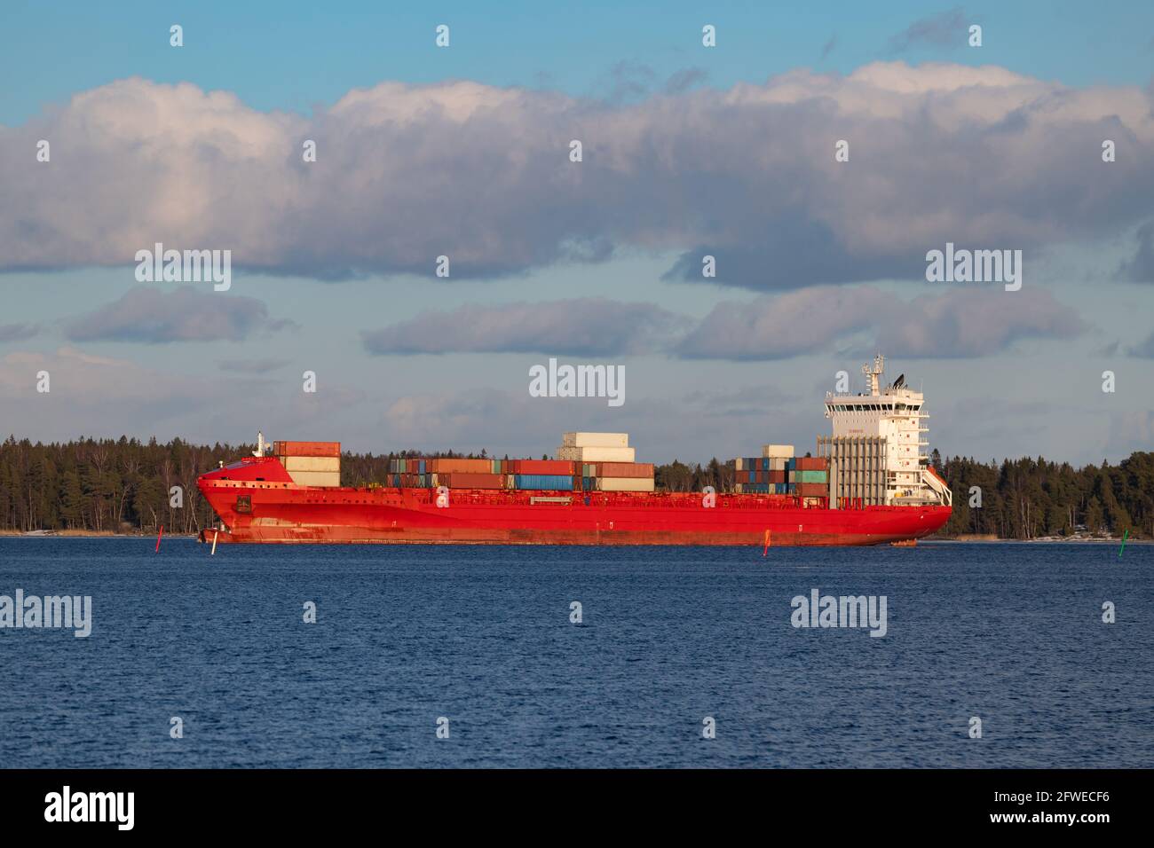 Rotes, teilweise beladenes Containerschiff, das über einen Archipel im Hafen von Vuosaari in Helsinki, Finnland, ankommt. Stockfoto