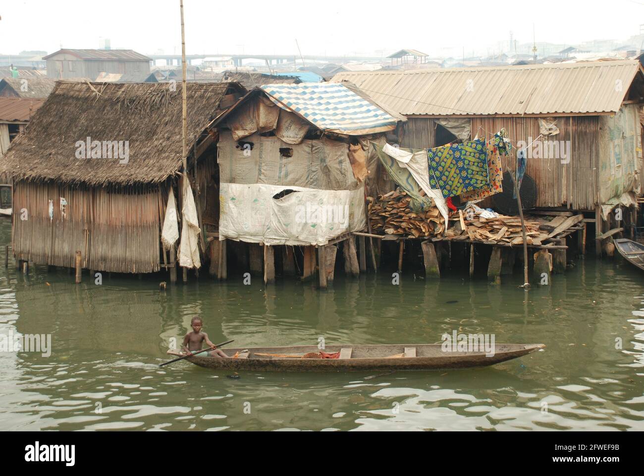 Ein Junge, der im Makoko Slum, Lagos, Nigeria, ein Kanu paddelt. Stockfoto