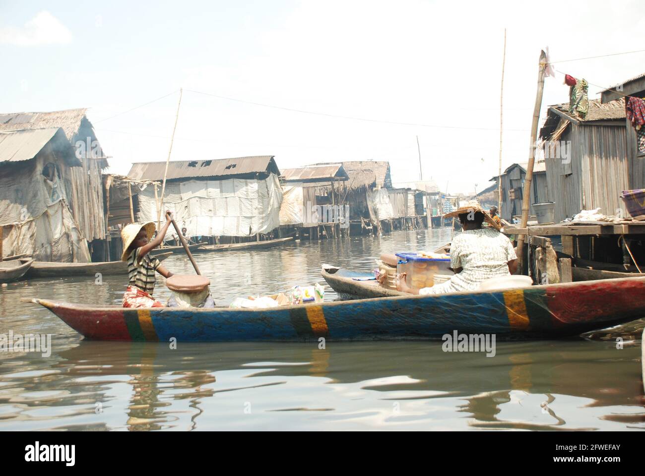 Frauen paddeln durch die Uferpromenade von Makoko, Lagos, Nigeria. Stockfoto