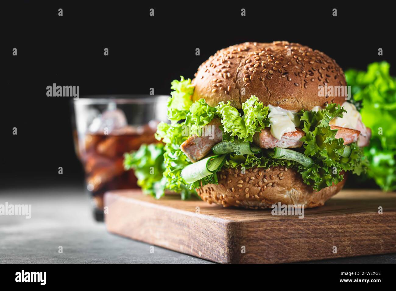 Köstlicher Lachsburger, serviert auf Holzbrett. Fischburger mit frischem  Salat, frischem Gemüse und Sauce. Gesunder knuspriger Fisch-Burger.  Selektiver Fokus Stockfotografie - Alamy