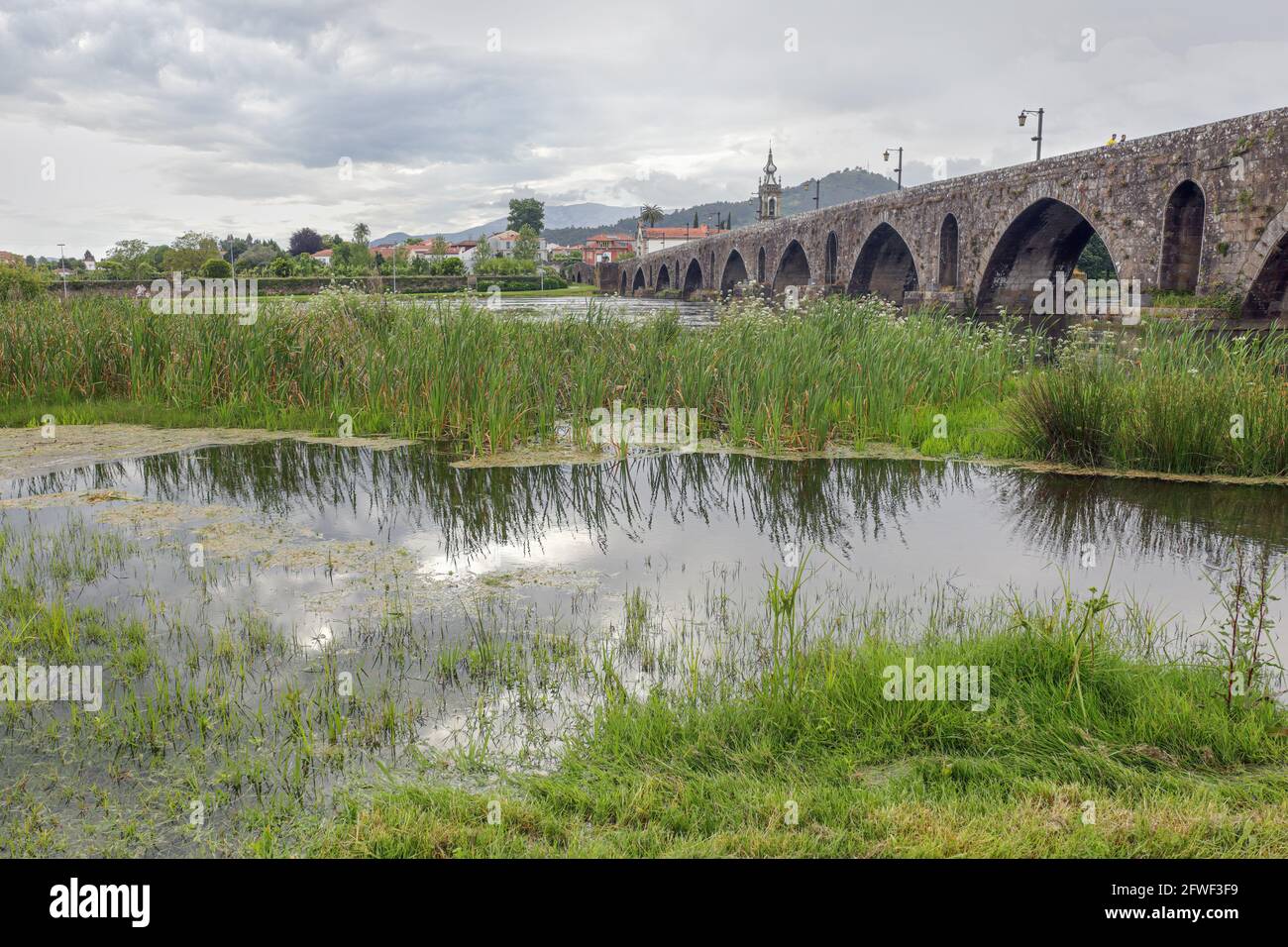 Alte Granitbrücke und Kirche aus der mittelalterlichen Stadt Ponte de Lima an einem regnerischen Tag. nordportugiesischer Weg nach Santiago de Compostela. Stockfoto