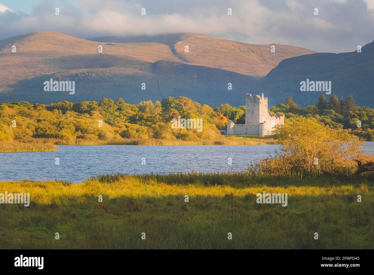 Golden Hour Sonnenuntergang Licht auf malerische Berglandschaft des historischen mittelalterlichen Ross Castle am Lough Leane See im Killarney National Park, County Kerr Stockfoto