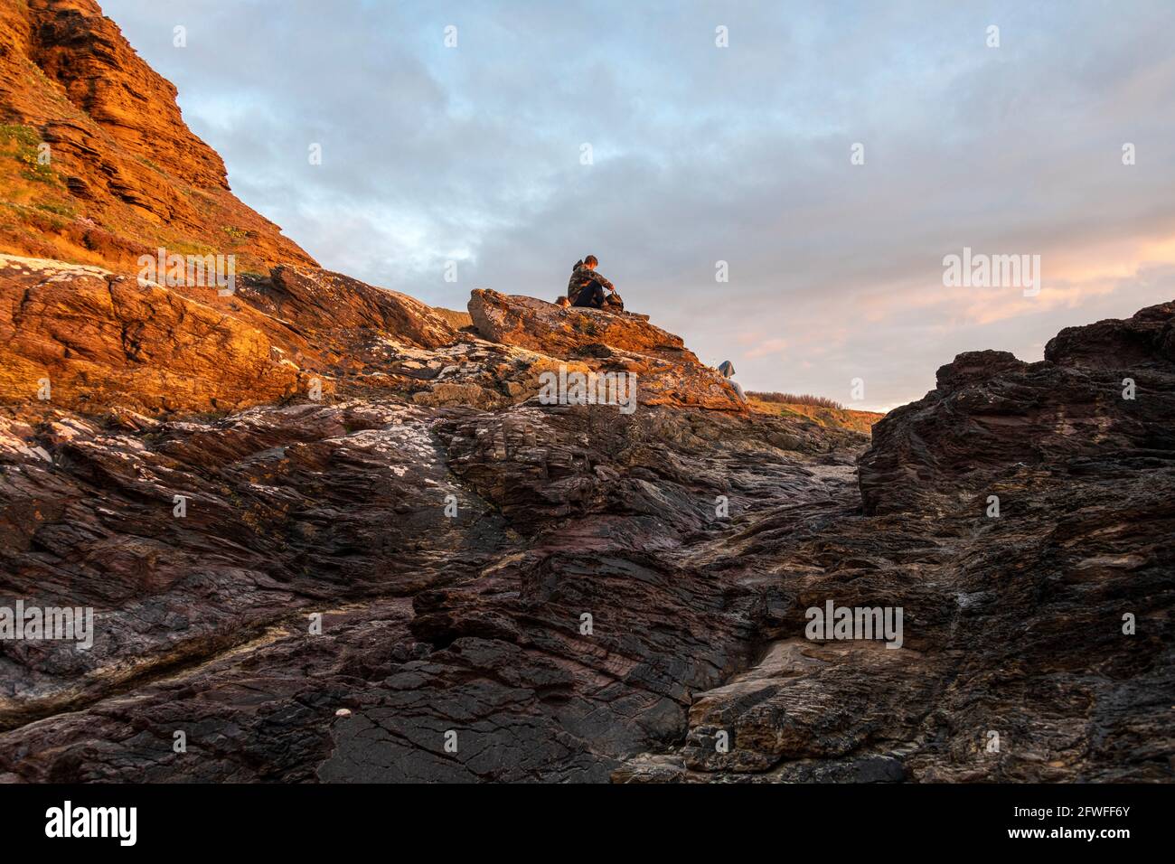 Ein Mann beobachtet den Sonnenuntergang über Greenaway Beach, Polzeath, Cornwall. Stockfoto
