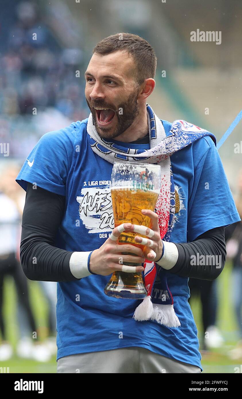 Rostock, Deutschland. April 2021. Fußball: 3. liga, Hansa Rostock - VfB Lübeck, 38. Spieltag. Torhüter Markus Kolke vom FC Hansa Rostock feiert mit einem hohen Glas Bier in der Hand den Aufstieg in die 2. Liga. Quelle: Danny Gohlke/dpa/Alamy Live News Stockfoto