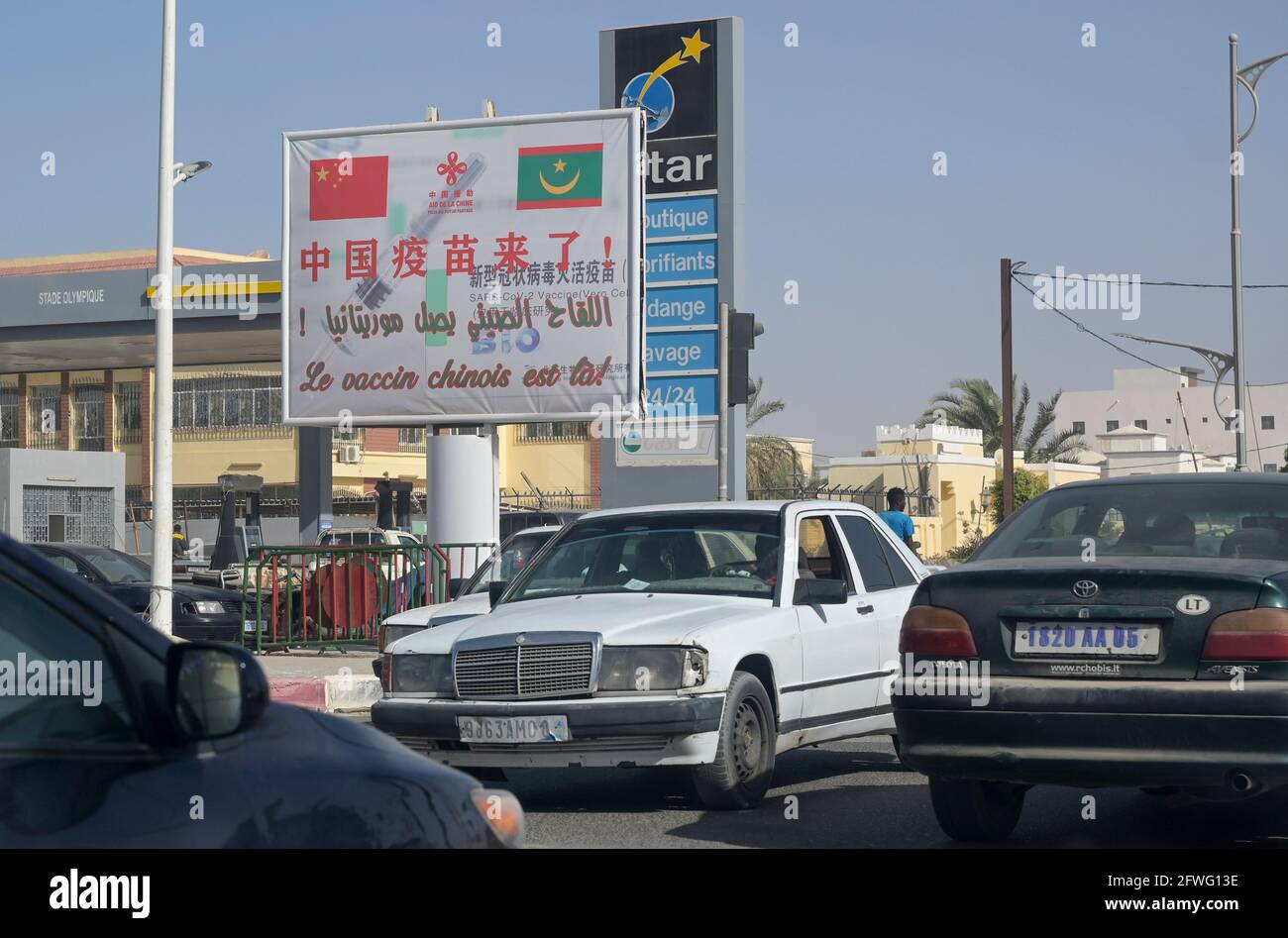 MAURETANIEN, Nouakchott, Corona-Pandemie, Plakatwand für chinesischen COVID-19-Impfstoff CoronaVac des chinesischen Pharmaunternehmens Sinovac Biotech, tzraffic, alte importierte Gebrauchtwagen aus Europa, deutsches Auto Mercedes-Benz Stockfoto