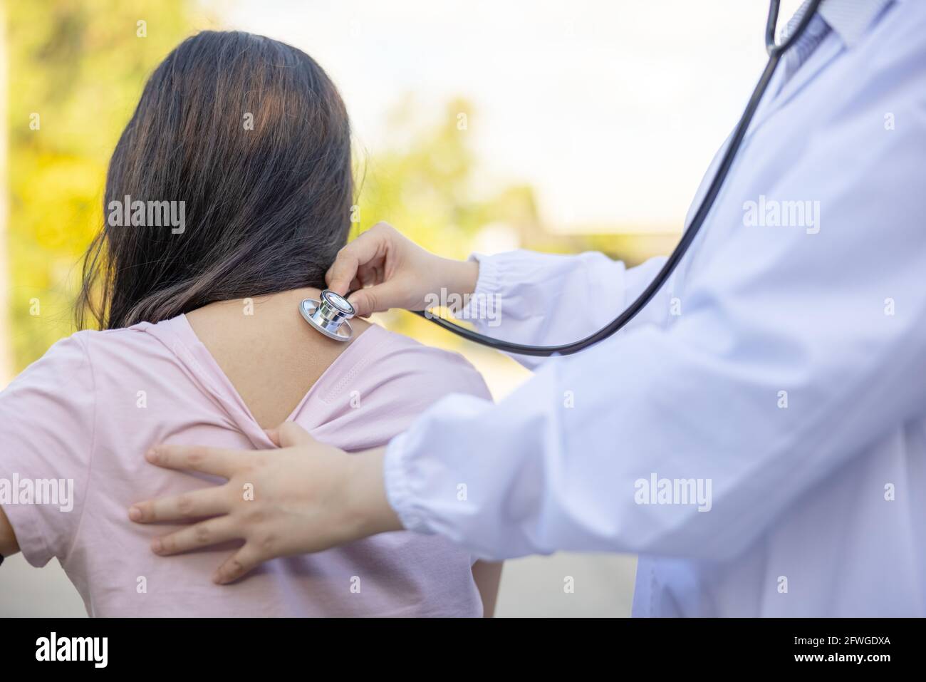 Der Arzt untersucht eine Patientin mit einem Stethoskop in einem Sommerpark. Stockfoto