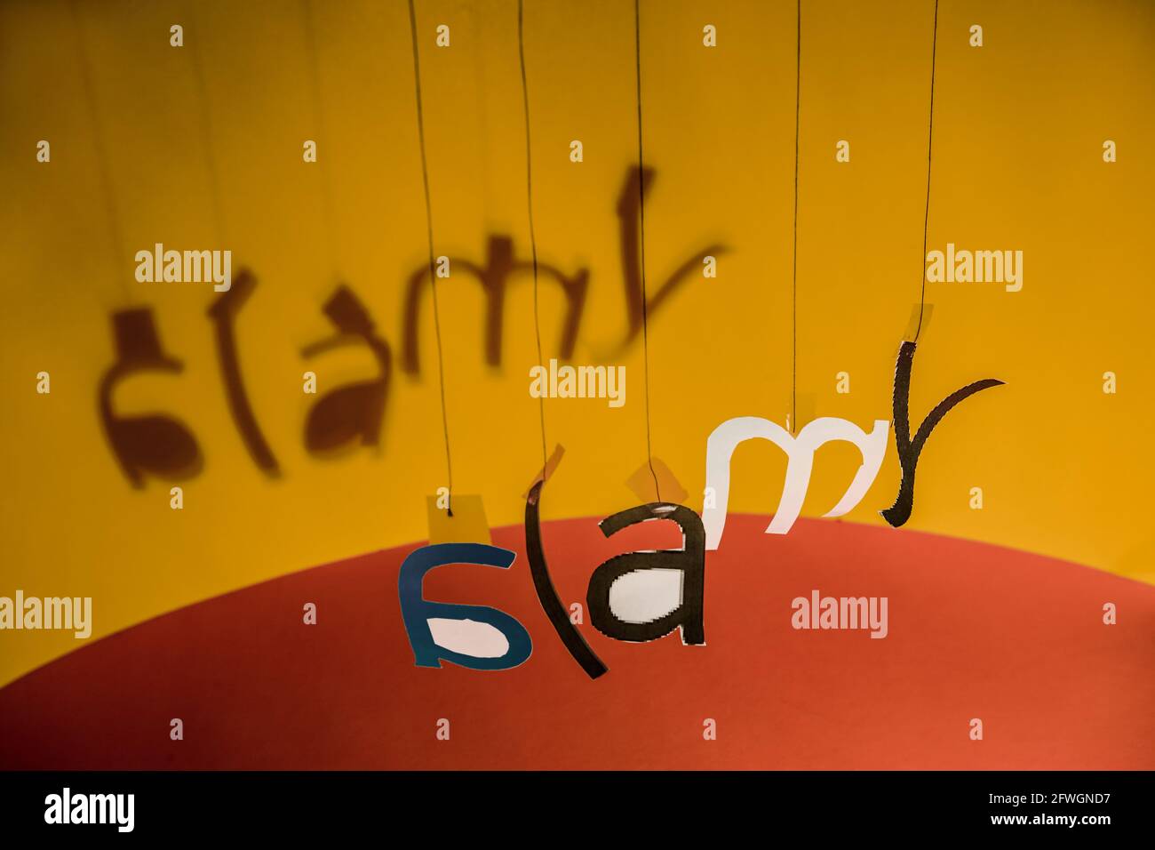 An Fäden hängende Buchstaben bilden in einer gewissen Unordnung das Alamy-Logo. Stockfoto