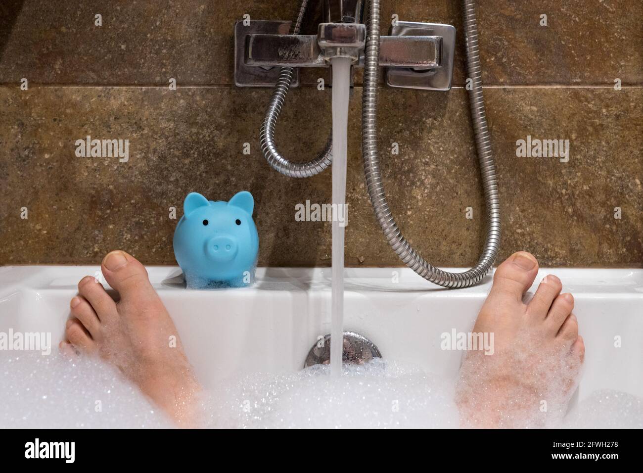 Wasser in die Badewanne und ein Sparschwein, Kostenkonzept und Verschwendung von sauberem Wasser Stockfoto