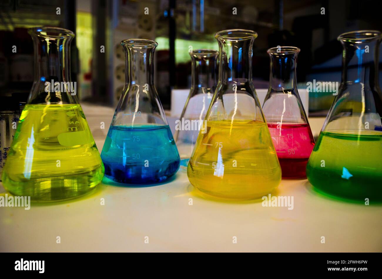 Bunte Lösung Zusammensetzung von konischen Kolben auf einer Bank ausgekleidet In einem Chemielabor mit Unschärfe-Hintergrund organischer Chemie Experiment Fotografie für b Stockfoto