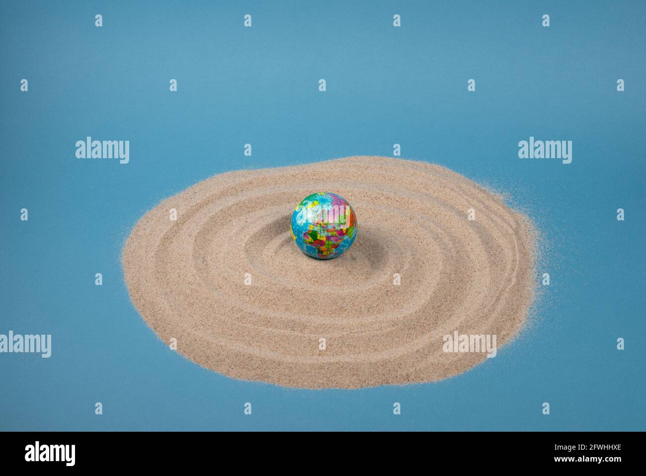 Weltkugel auf weißem Sand und blauem Hintergrund. Planet Earth Spielzeug. Stockfoto