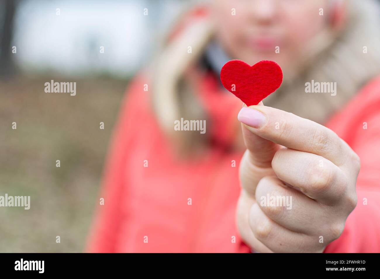 Das Mädchen hält ein Herz in der Hand als Zeichen der Liebe. Stockfoto