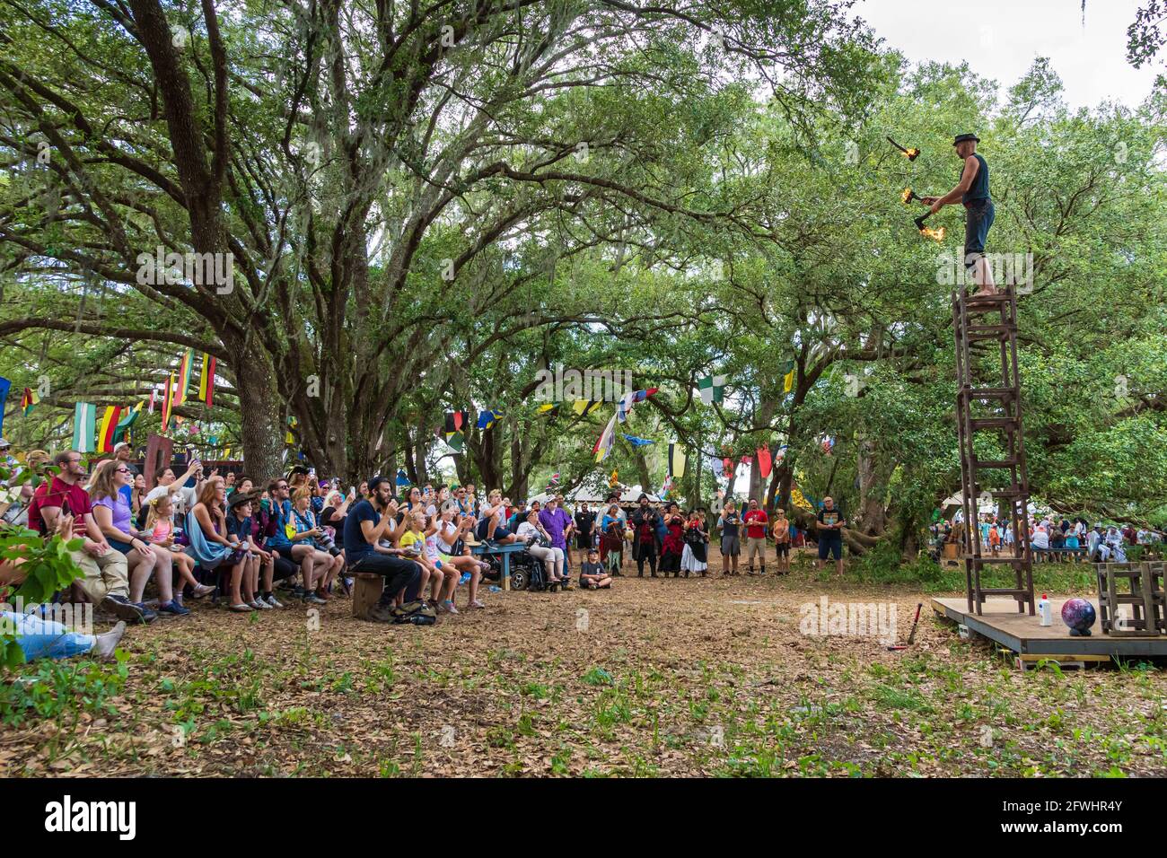 Ichabod Wainwright jongliert mit flammenden Äxten und steht auf gestapelten Stühlen beim Bay Area Renaissance Festival, Withlacoochee River Park, Dade City, Florida Stockfoto