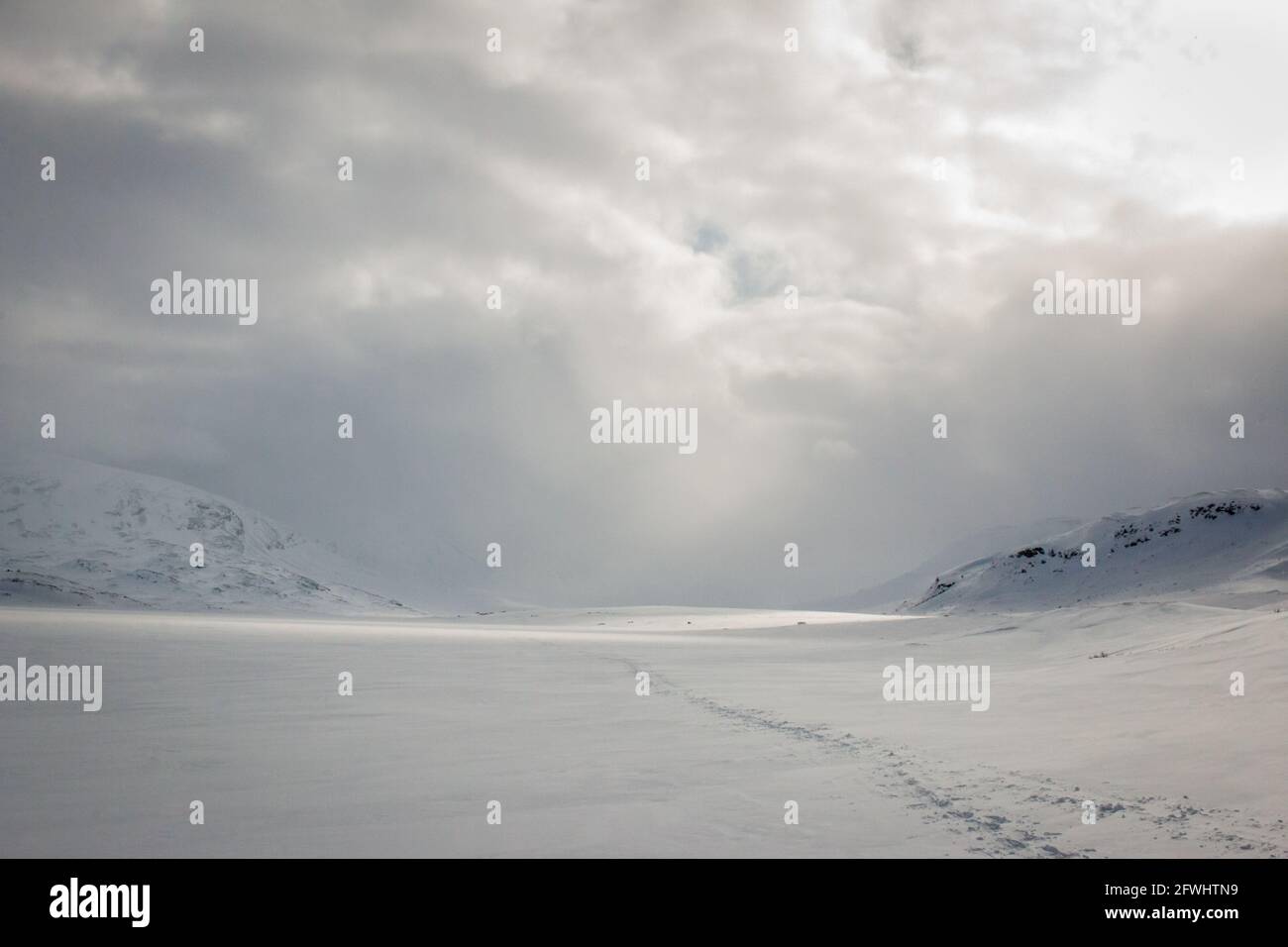 Schneeschuhwandern auf einem gefrorenen See, der sich bei Sonnenuntergang den Alesjaure Hütten nähert, Kungsleden Trail, Schwedisch Lappland, April 2021. Stockfoto