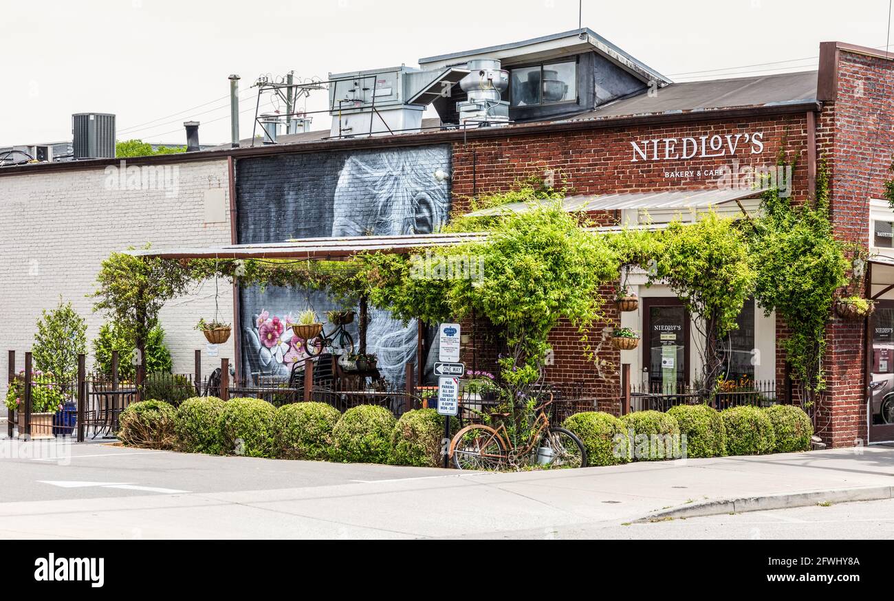 CHATTANOOGA, TN, USA-9 MAY 2021: Niedlov's Bakery & Cafe. Seitenwand außen mit kleiner überdachter Veranda zum Essen. Üppiges Grün. Stockfoto